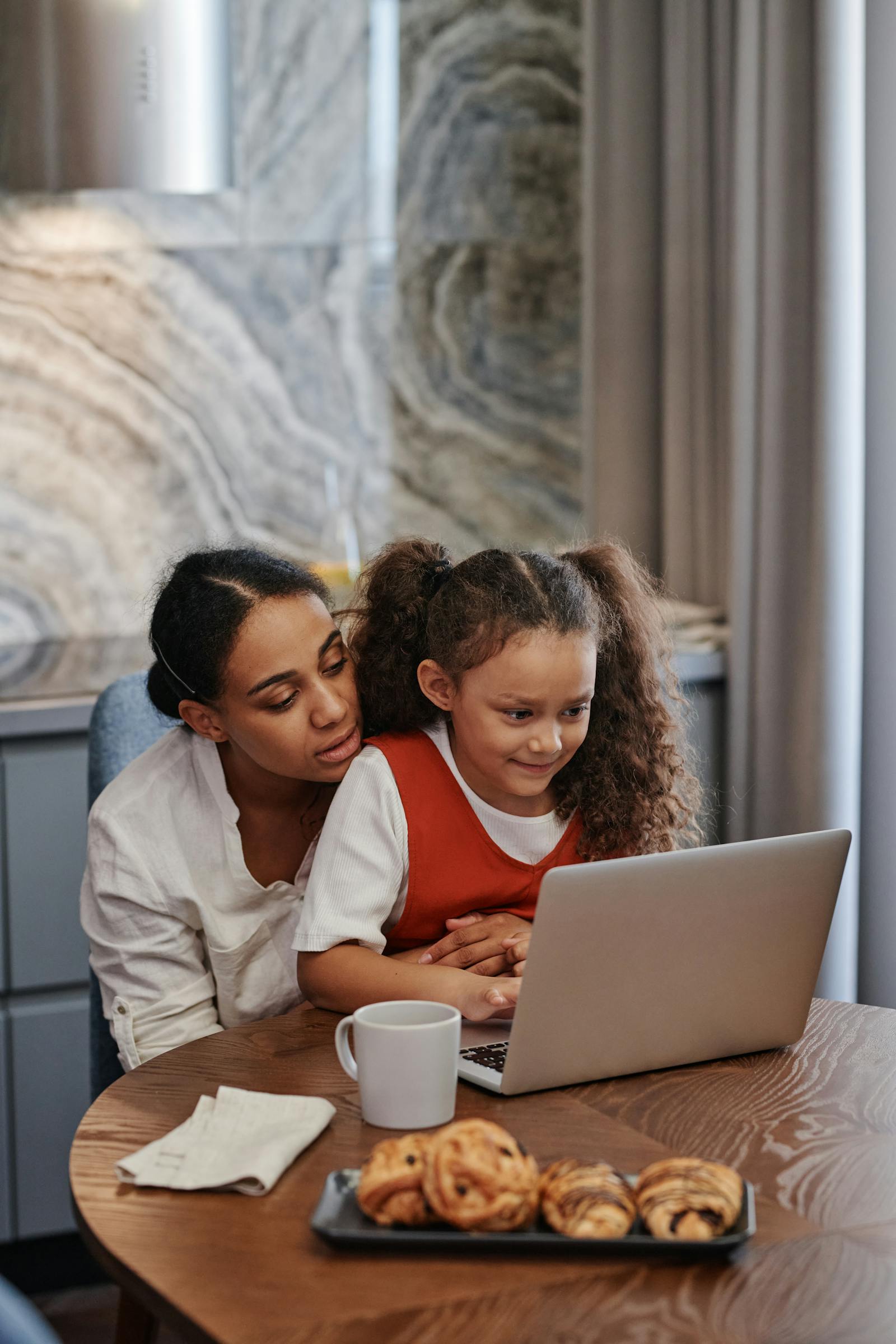 Mother and daughter working on a laptop at home